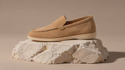 Premium Suede Loafers in Caramel, Black and Marine Blue, rotating on a stone display.